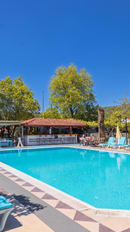 a large swimming pool with chairs and a building at Yakamoz Hotel Fethiye in Fethiye