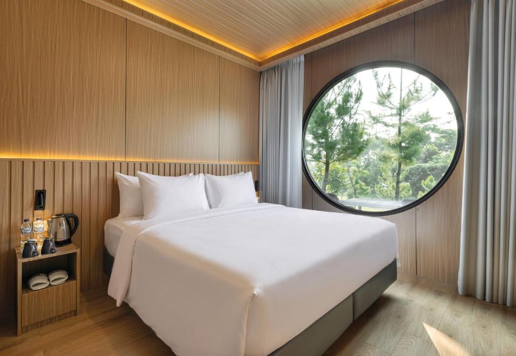 a bedroom with a large bed and a round window at The Glamping at ARTOTEL Pelangi Park in Pasirkuda