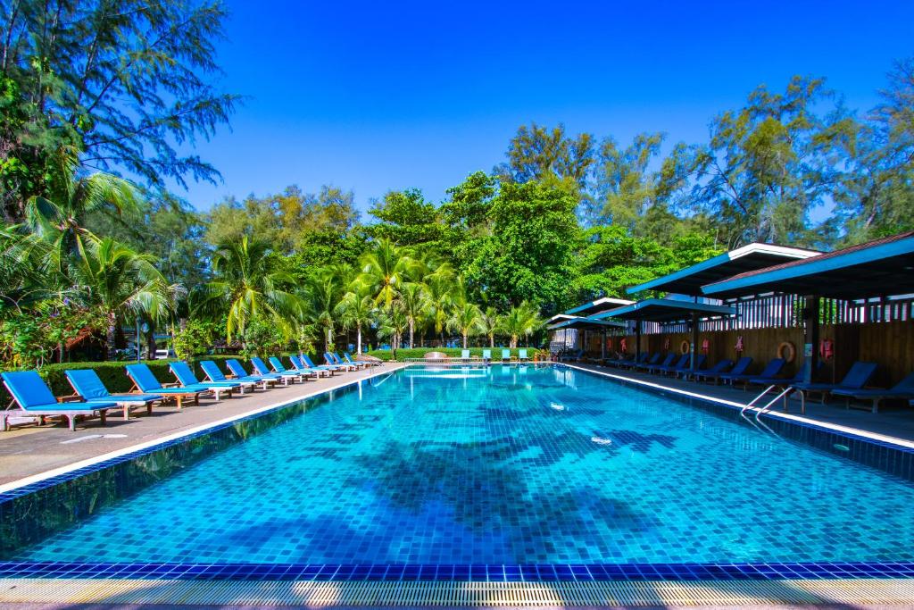 a large swimming pool with blue chairs and trees at Naiyang Park Resort - Beachfront Escape in Nai Yang Beach