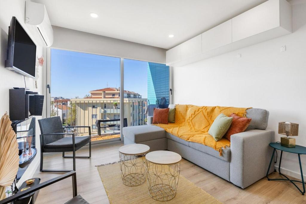 a living room with a couch and a large window at Blue Breeze Espinho | Pool View, Gym & Balcony in Espinho