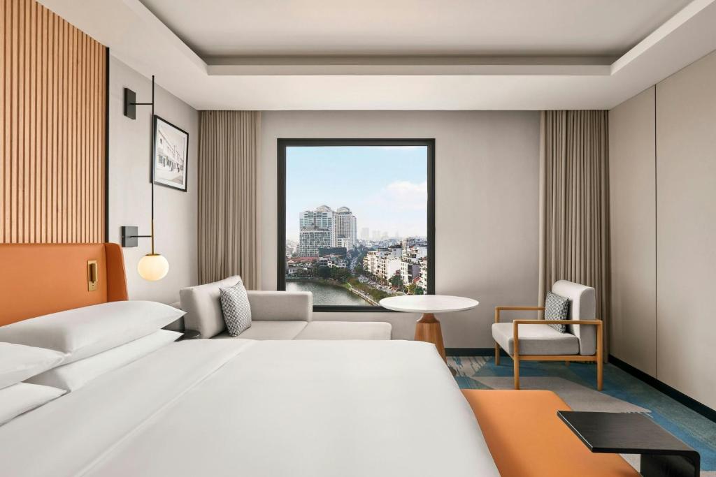a hotel room with a large white bed and a window at Sheraton Hanoi Hotel in Hanoi