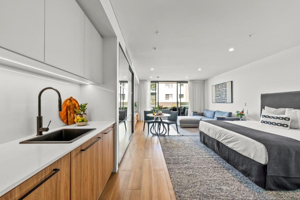 a bedroom with a bed and a kitchen with a sink at Kove Apartment - G02 in Kiama