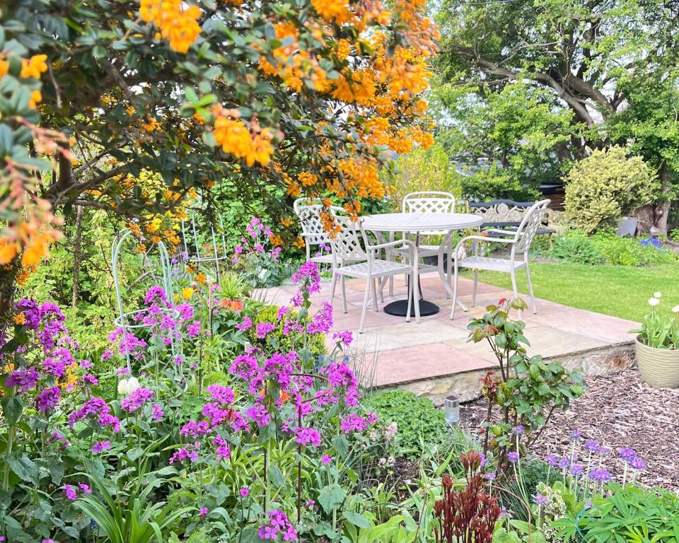 a table and chairs in a garden with flowers at Atte Combe Cottage, Hadrian Wall Country in Acomb