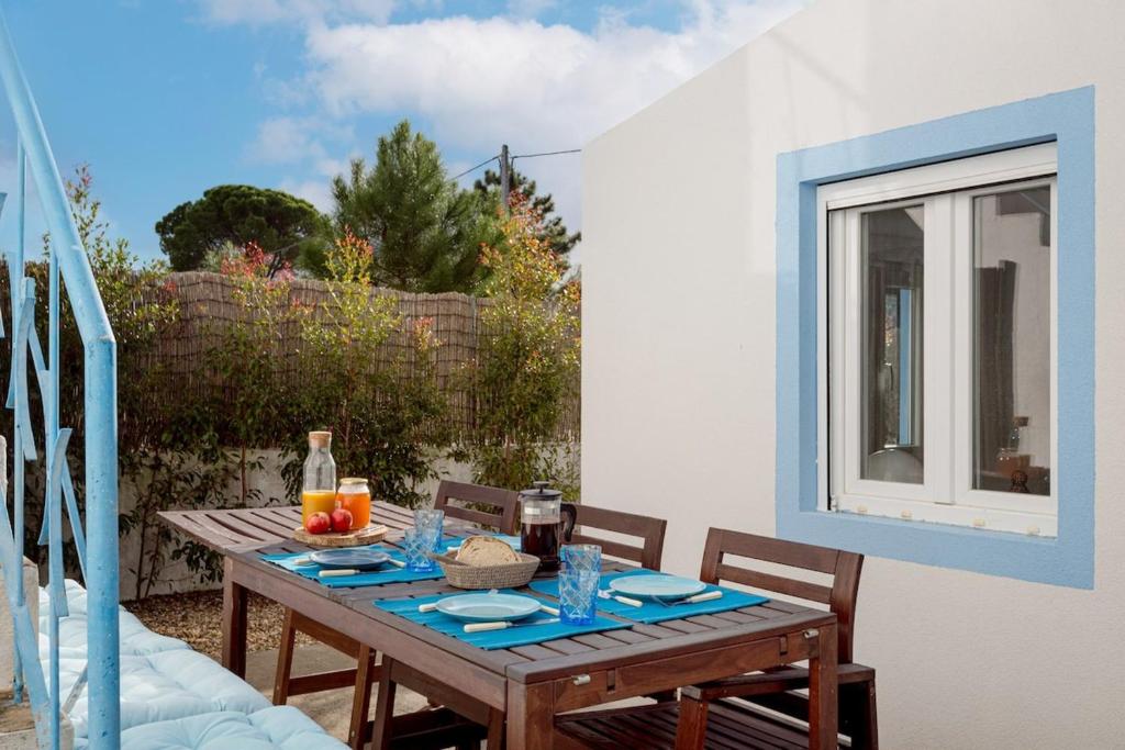 a wooden table with blue plates on a patio at Pinhal da Praia em Melides in Quinta da Cascalheirinha