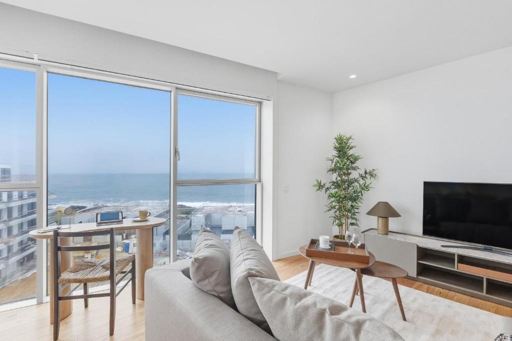 a living room with a couch and a table and a tv at Sal D’Ouro Skyline & Sea Views in Canidelo