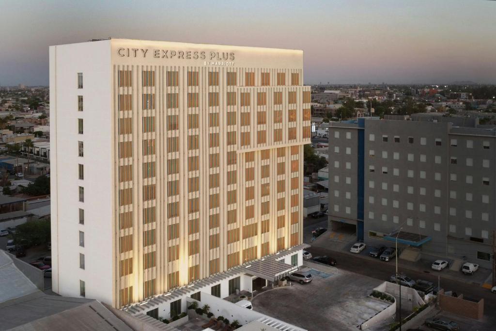 a tall white building with the city express shuttle on it at City Express Plus by Marriott Mexicali in Mexicali