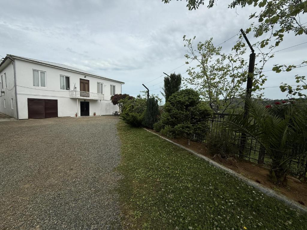 ein weißes Haus mit einem Zaun und einer Kiesauffahrt in der Unterkunft Sameba House in Khuts'ubani