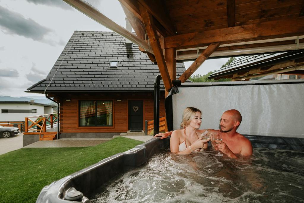 a man and a woman sitting in a hot tub at Zrub Azarka s vírivkou a saunou in Beňuš