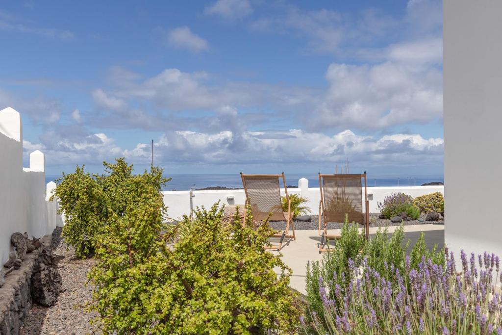 two chairs sitting on the beach with the ocean in the background at Glück House In Las Norias in Las Manchas