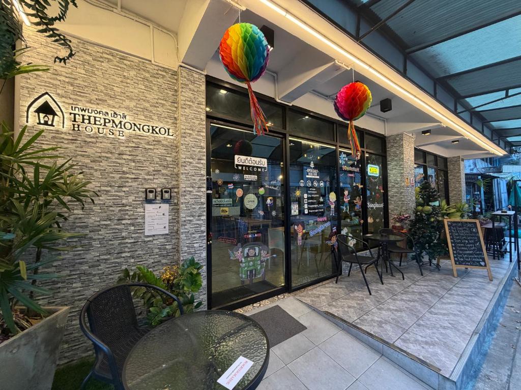 a store front with tables and chairs and colorful balloons at Thepmongkol House in Bangkok