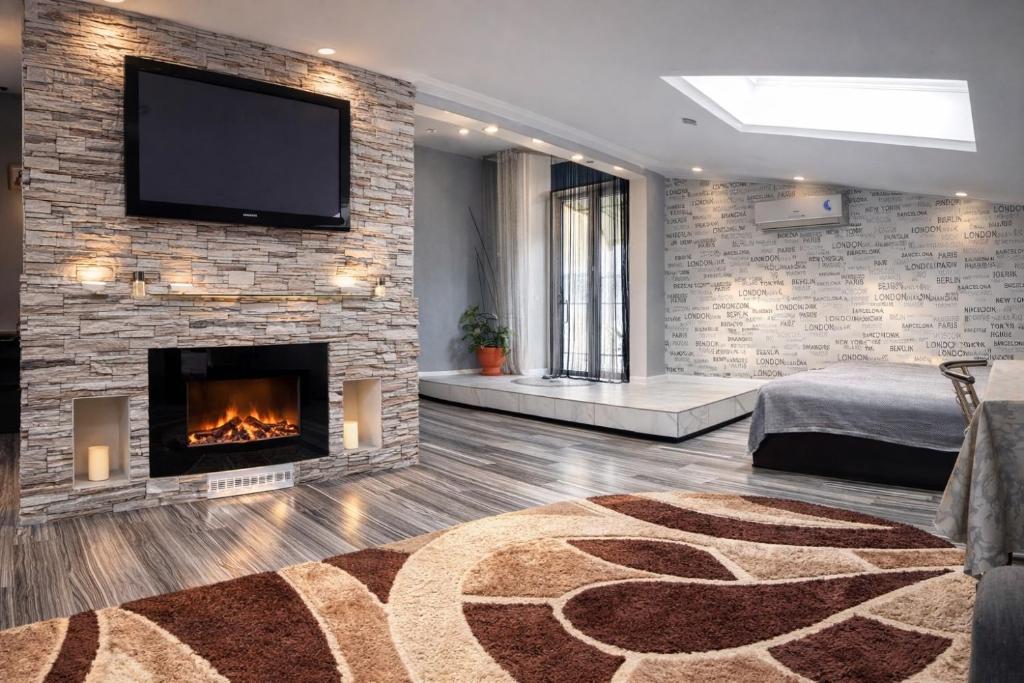 a living room with a fireplace and a tv on a brick wall at Stone City Apartment in Park Zone in Kamianets-Podilskyi