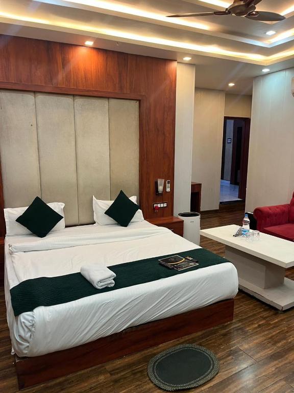 a bedroom with a large bed and a red couch at Hotel V Square in Lucknow