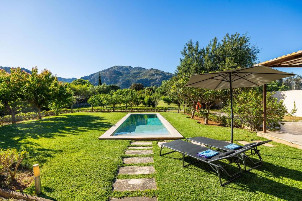 a backyard with a pool and an umbrella and a bench at Alfonsa in Pollença