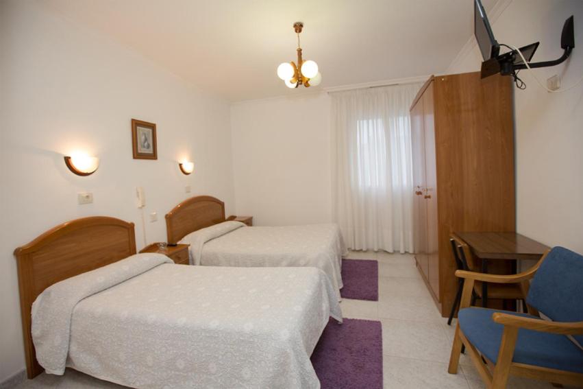 a hotel room with two beds and a table at Hotel Venezuela in Villalba