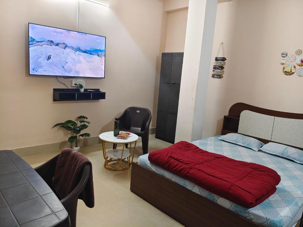a bedroom with a bed and a table and a tv at JM Niwas in Guwahati