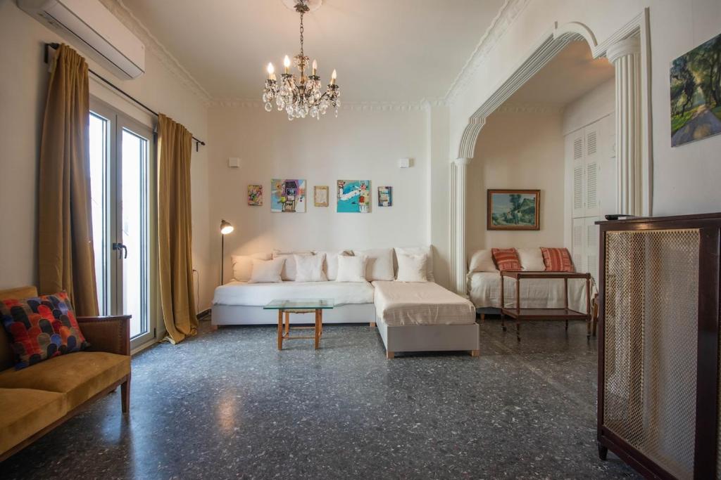 a living room with a white bed and a chandelier at SunWave Residence in Agios Nikolaos