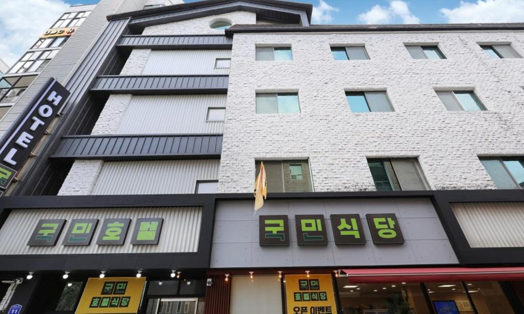a tall white building with green numbers on it at Gukmin Hotel in Gumi