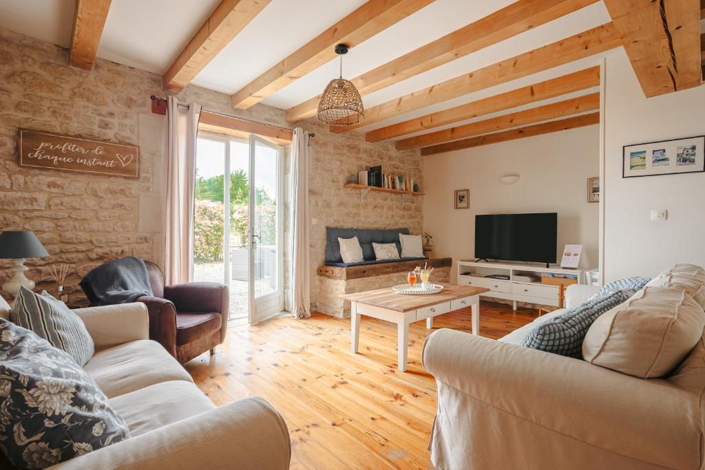 a living room with a couch and a tv at Ambre à la Rochelle in Vergné