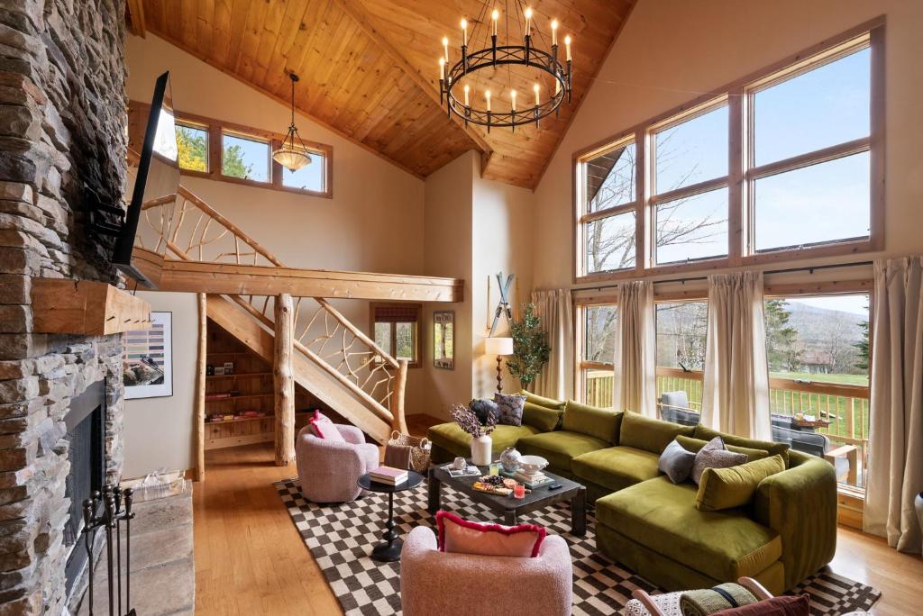 a living room with a green couch and a fireplace at Velvet Timber Haus | HotTub, Sauna, Firepit, Games in Windham