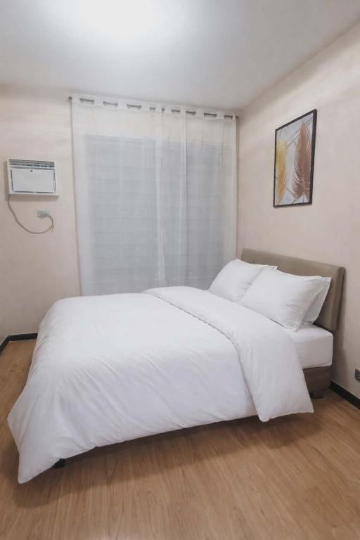 a bedroom with a white bed and a window at Suite City view in Manila