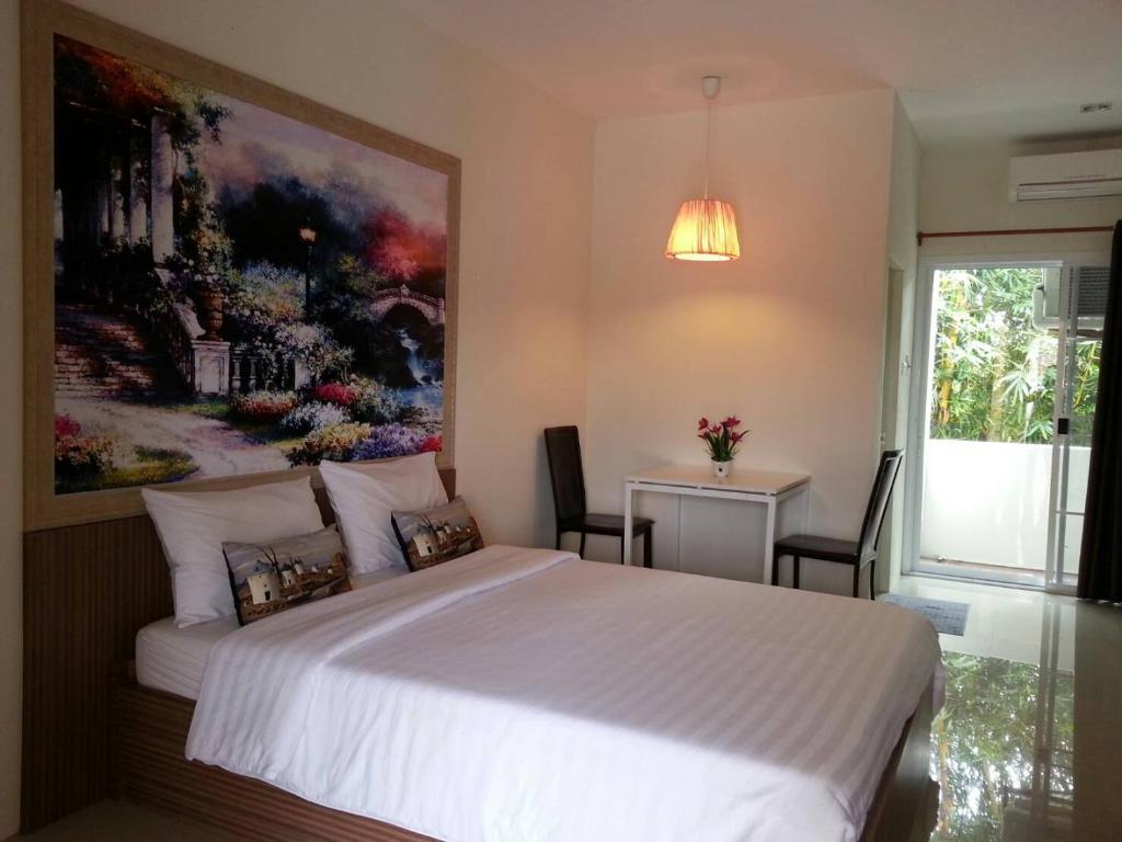 a bedroom with a large white bed with a painting on the wall at The Nine Mansion in Ubon Ratchathani