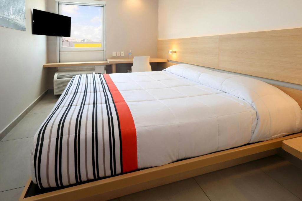 a large bed in a room with a television at City Express Junior by Marriott Cancun in Cancún