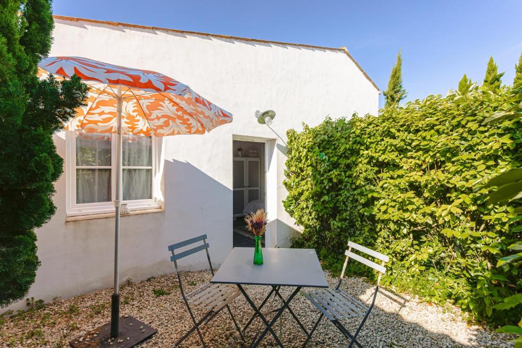 a table and chairs and an umbrella in front of a house at Gite Les Jardins d'Harmonie in Bourgneuf