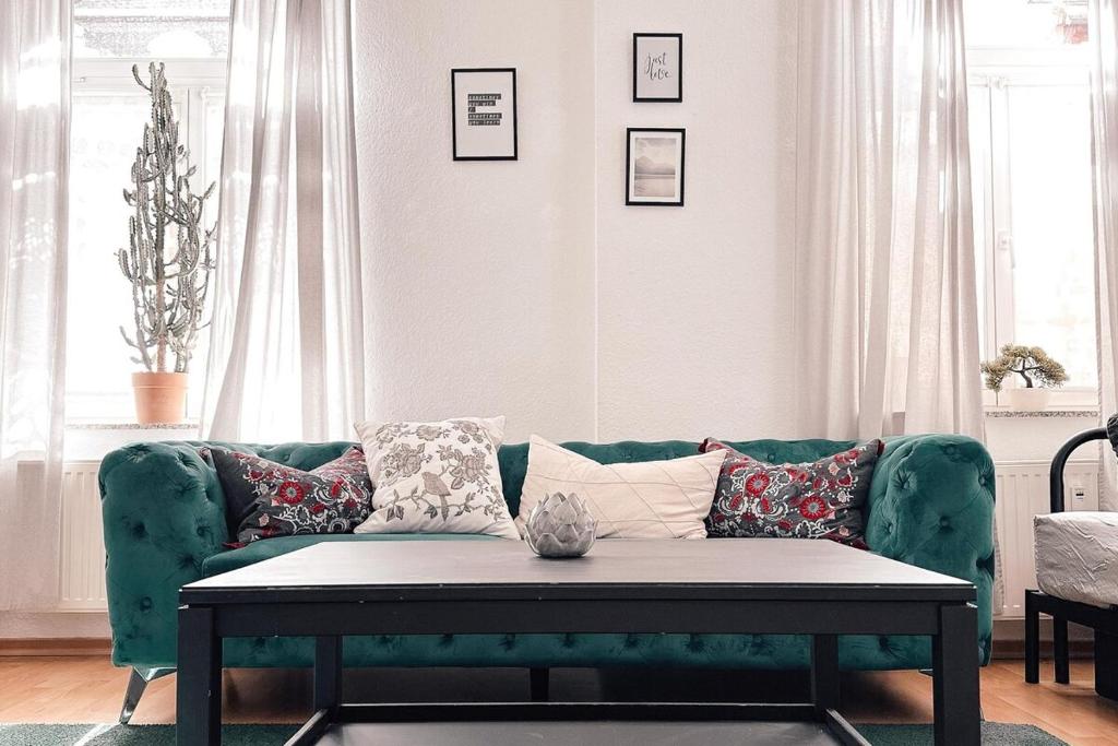 a living room with a green couch with pillows at City Retreat Zwickau mit Balkon zum Innenhof in Zwickau