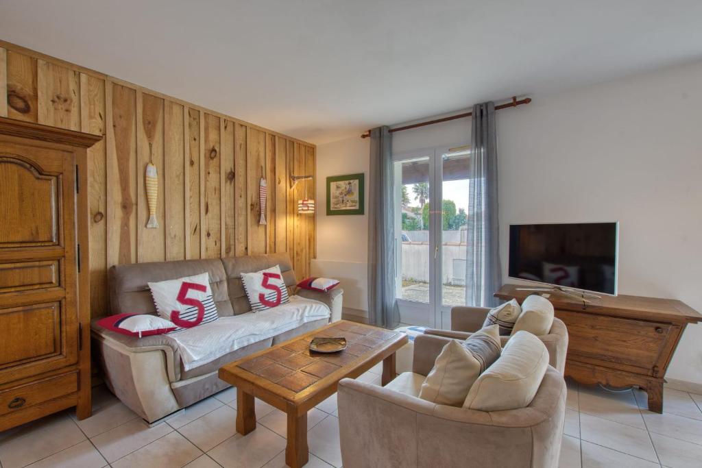 a living room with two couches and a tv at Maison Oléron - Welkeys in Dolus-d'Oléron