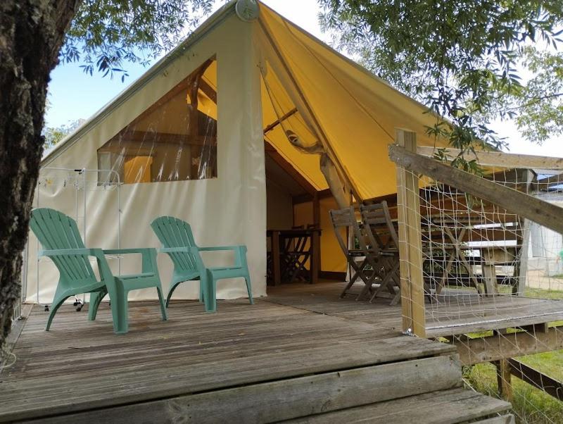 two green chairs sitting on a deck in front of a tent at Camping du pont d'Oust in Peillac