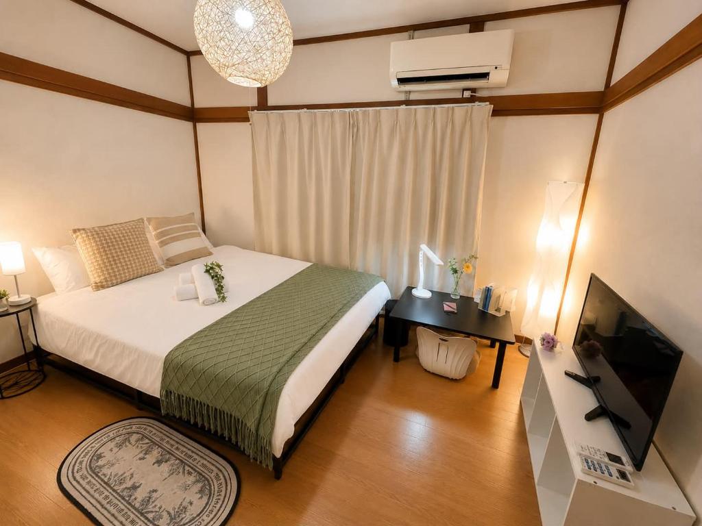 a bedroom with a large bed and a television at Yoshimi Stay Kawaguchi in Kawaguchi