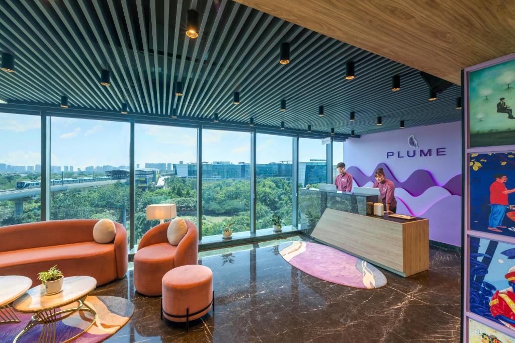 a lobby with orange furniture and a woman standing at a counter at Plume Hotels, India Expo Mart, Greater Noida in Greater Noida
