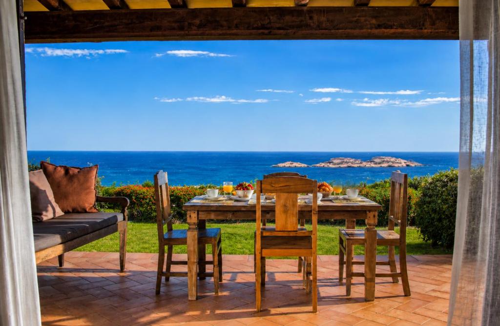 a table and chairs on a patio with a view of the ocean at Big Pevero Sea View House 7 Two Bedrooms in Porto Cervo