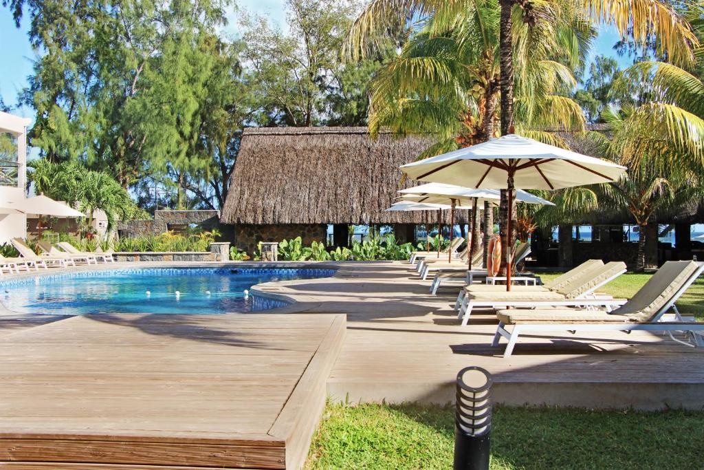 a swimming pool with lounge chairs and an umbrella at Villas Mon Plaisir in Pointe aux Piments