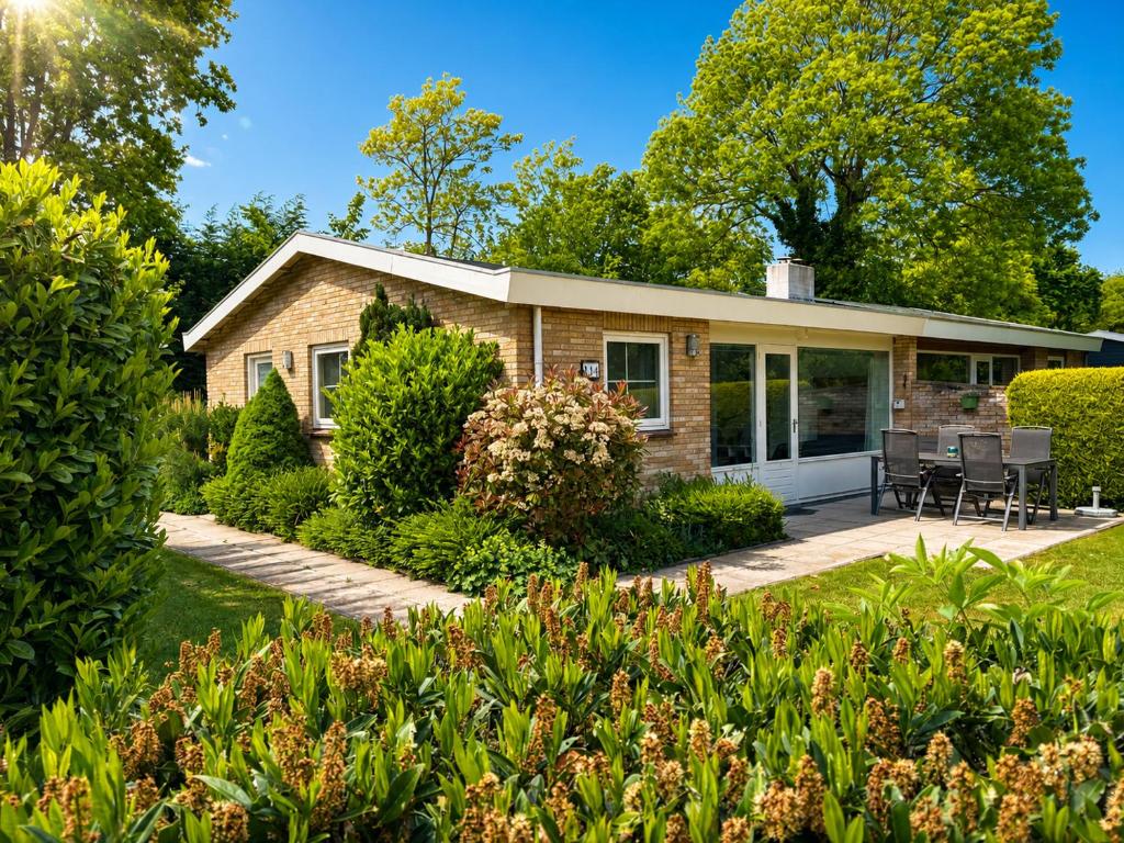 a brick house with a patio and landscaping at De Duinrand in Oostkapelle