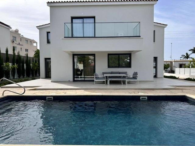 a house with a swimming pool in front of a house at Villa Cloxania Coral in Peyia