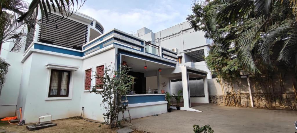 a white house with blue trim and palm trees at Tamil Megam Villa in Chennai
