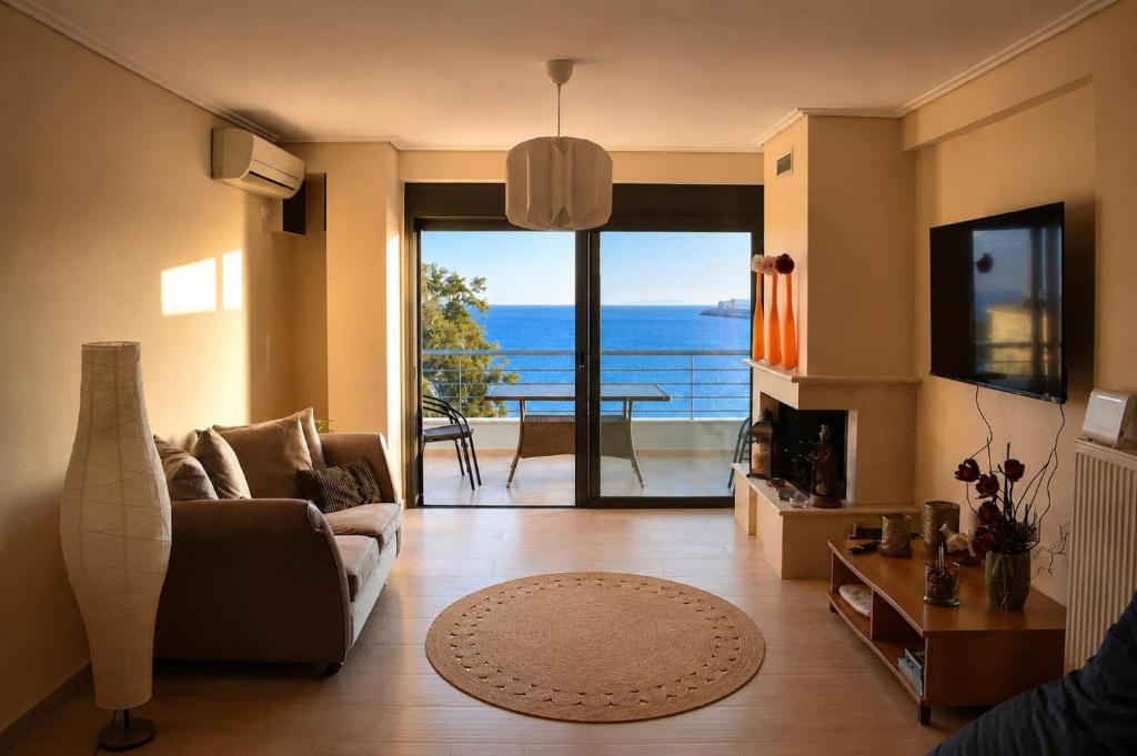 a living room with a couch and a view of the ocean at Alia Beachfront Penthouse with Sea View in Lefkandi Chalkidas