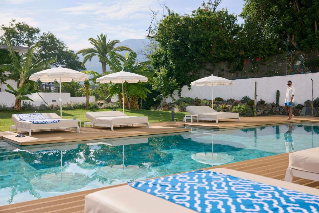 a swimming pool with lounge chairs and umbrellas at TUI BLUE Atlantic Hills in Puerto de la Cruz