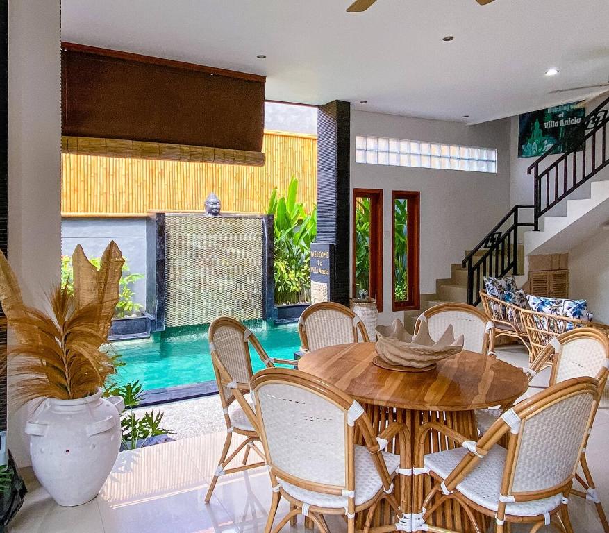 a dining room with a table and chairs and a pool at Villa Aniela Legian in Legian
