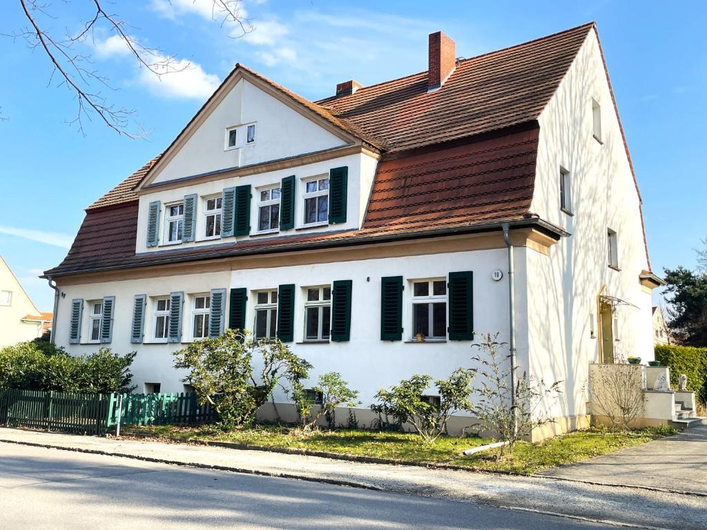 a white house with green shutters on a street at Villa Seenswert in Lauta