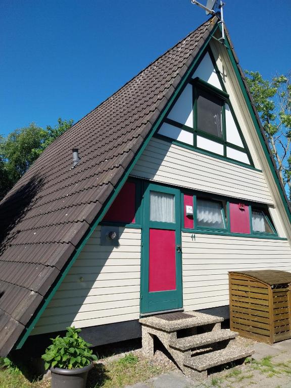 a house with a gambrel roof with red and green doors at Nordseenest in Butjadingen