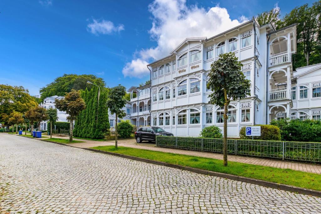 a large white building on a cobblestone street at Villa Eden II in Binz