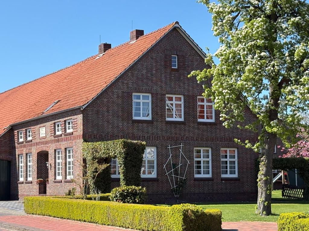a brown brick house with white windows and a tree at Ferienhaus Franzen 35679 in Uplengen