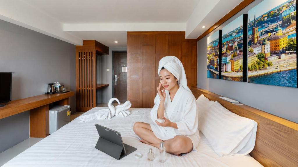 a woman sitting on a bed with a laptop at PP@Hotel Rangsit in Pathum Thani
