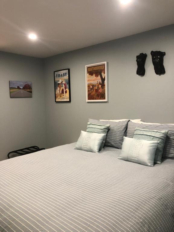 a bedroom with a bed with three pictures on the wall at Truffle Ridge Vineyard Stay in Martinborough