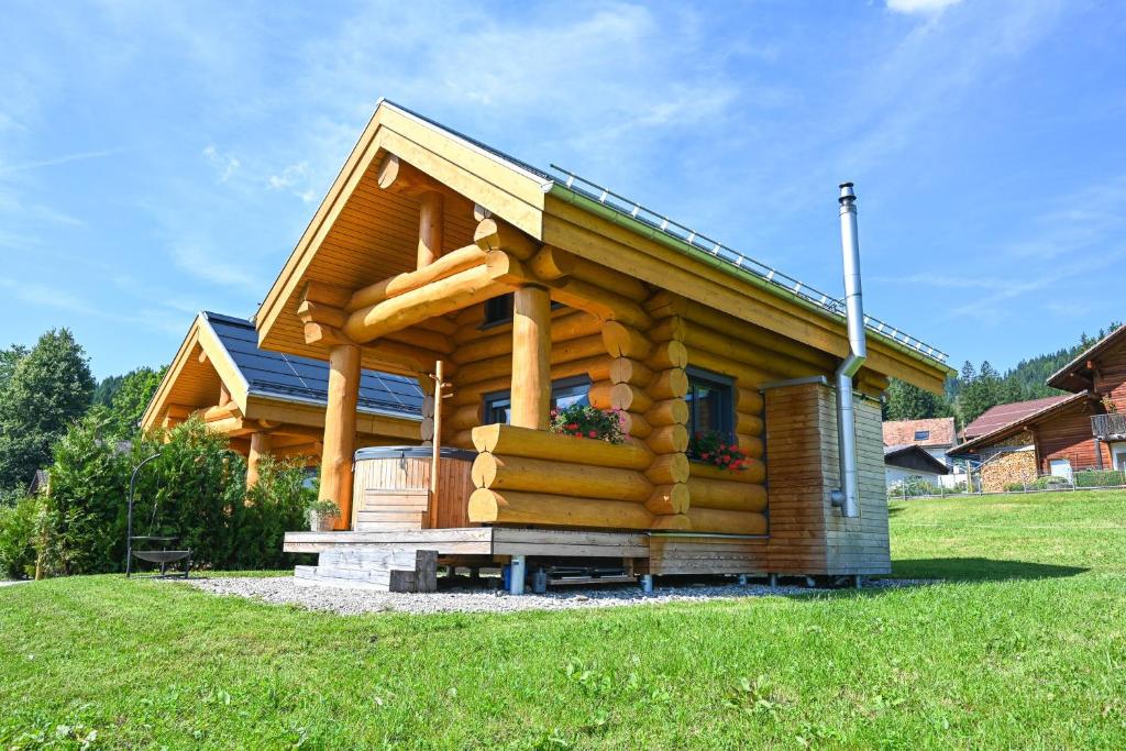 a log cabin with a large porch on a green field at Mein Refugium Luxury Tiny House in Unteriberg