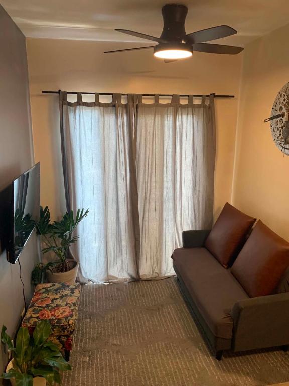 a living room with a couch and a ceiling fan at The Pine Lush Hideout in Baguio