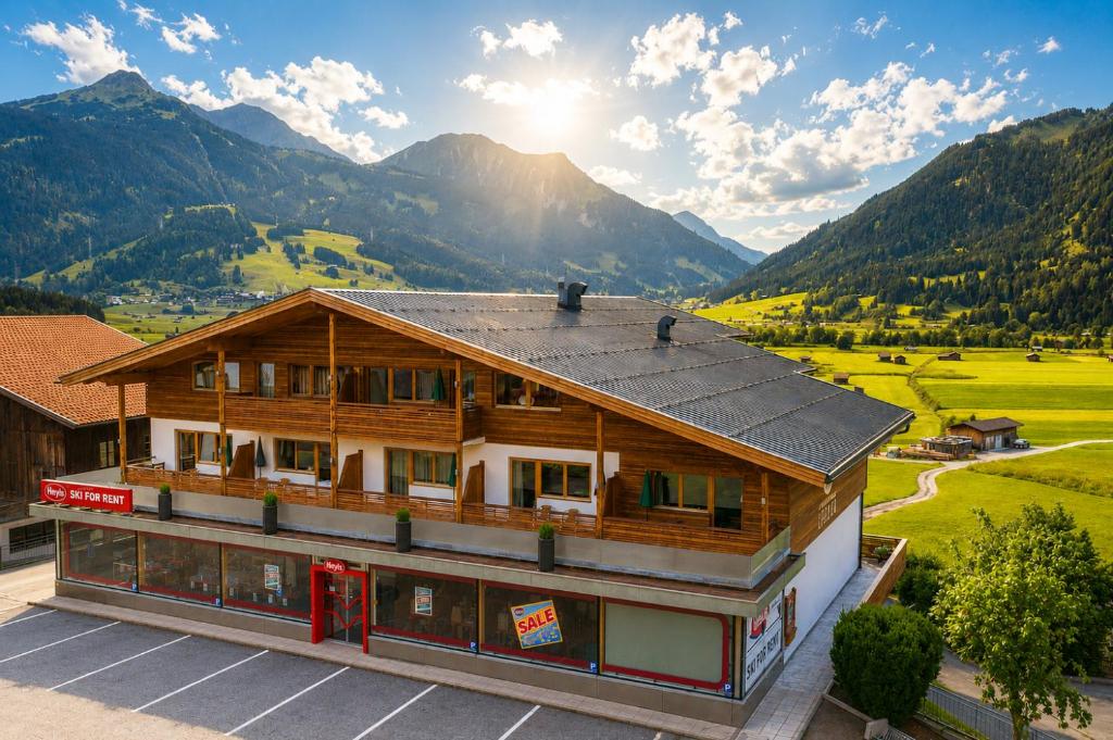 a large wooden house with mountains in the background at Appartementhaus Leitner in Ehrwald