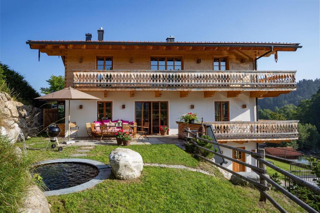 a house in the mountains with a pond at Ferienwohnungen Fendl in Fischbachau